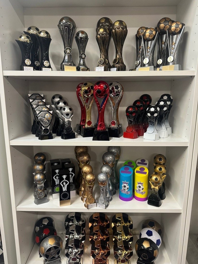 Shelves of black, red and gold football trophies